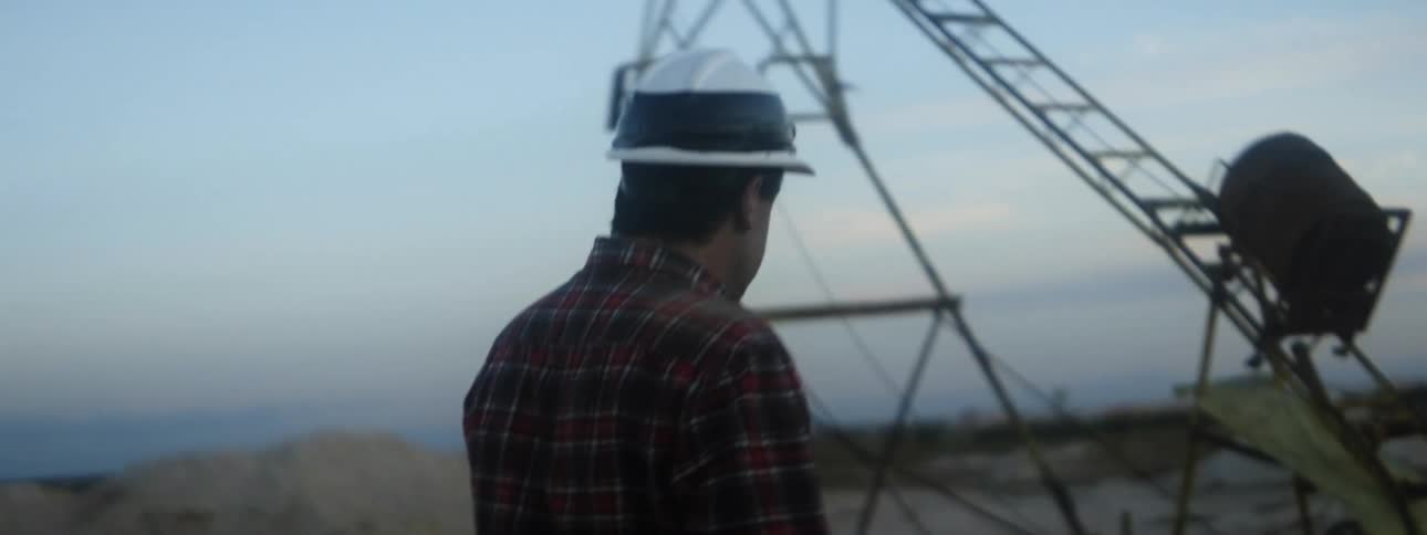 A worker wearing a hardhat walks past a metal structure