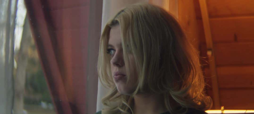 A sad looking teenage girl looks out the window