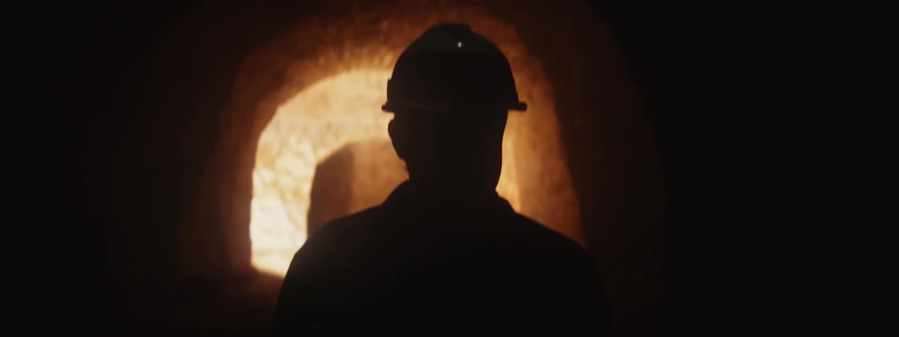 A man wearing a hardhat is walking through a mine shaft