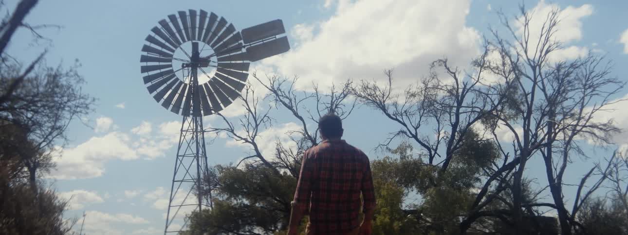 A man walking out near a windmill