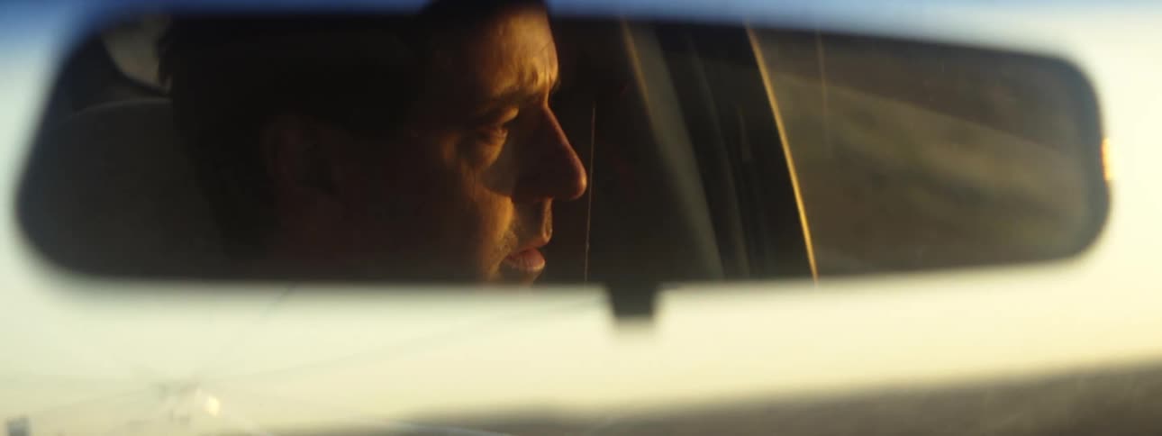 Reflection on a rearview mirror of a man driving a car at morning