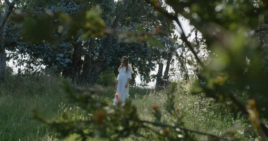 A woman walks across a grassland and looks around