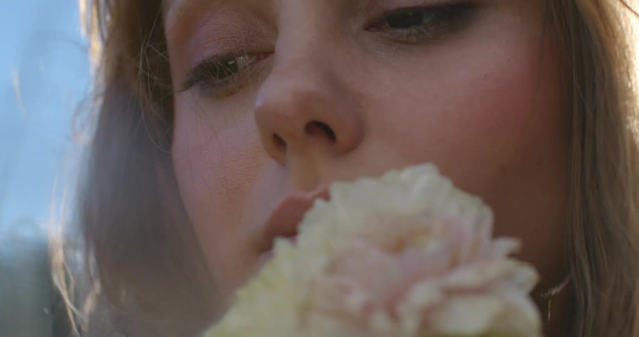 A woman holds a wildflower up to her nose to smell