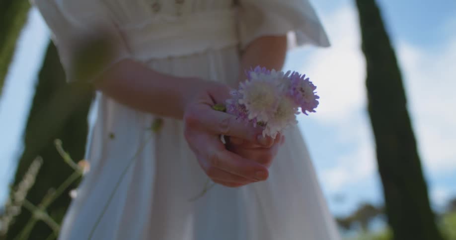 A woman poses with a handpicked bouquet of wildflowers