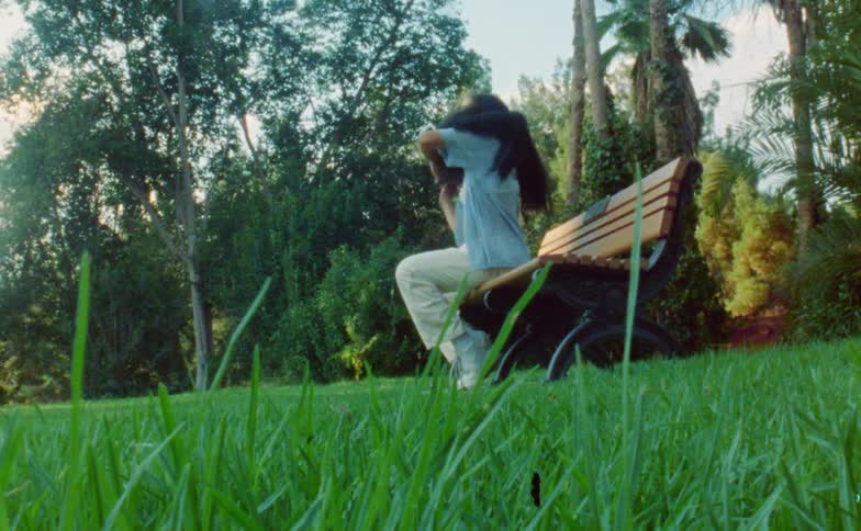 Young flexible woman dances while sitting on a bench in a park at morning