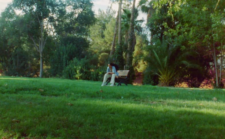 Young flexible woman dances while sitting on a bench in a park at morning