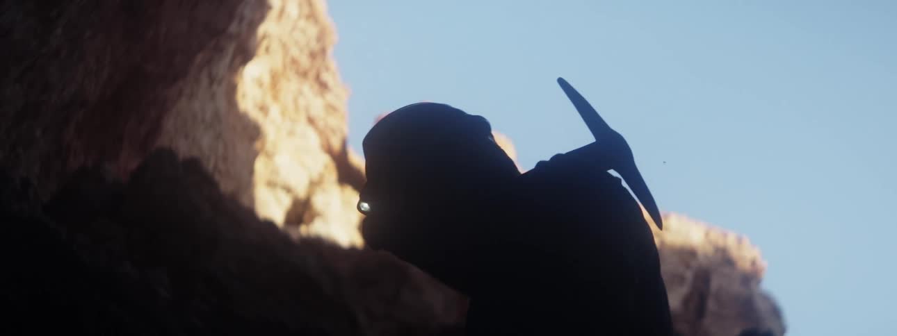 A miner heading into a mine with a pick axe