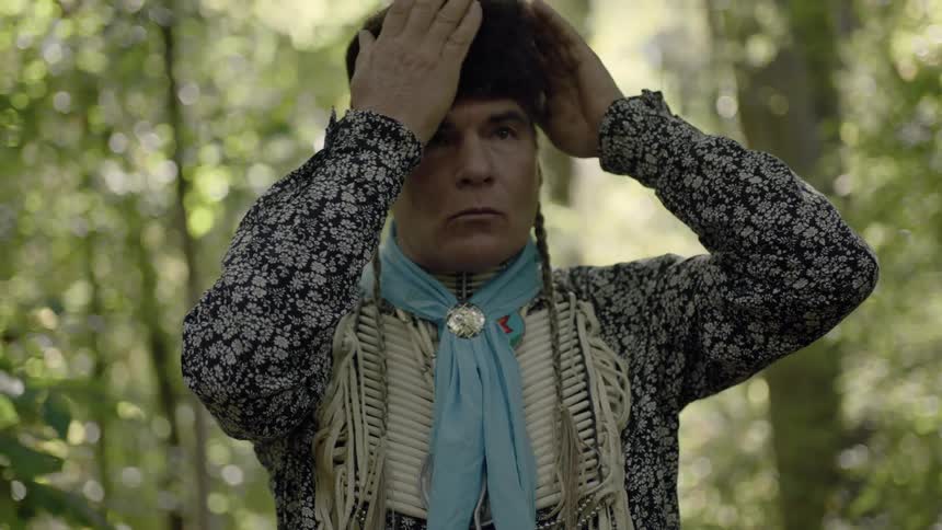 An american indian male puts on a hat
