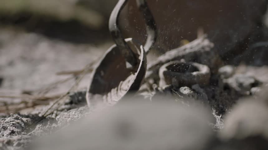 Someone turns a bowl over in a pile of ashes