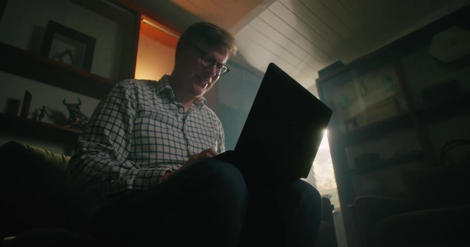 A man is happy as he types on a laptop