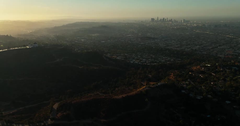 Dark hillsides and mountain ridge overlooking the valley full of homes and la city skyline in the distance