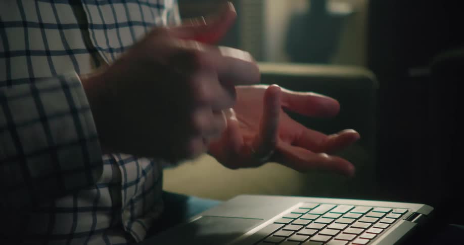 A man is sitting down in front of his laptop computer counting on his fingers