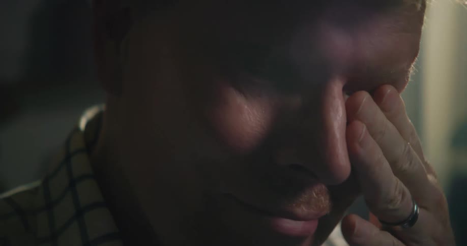 A man rubs his eyes after taking off his glasses