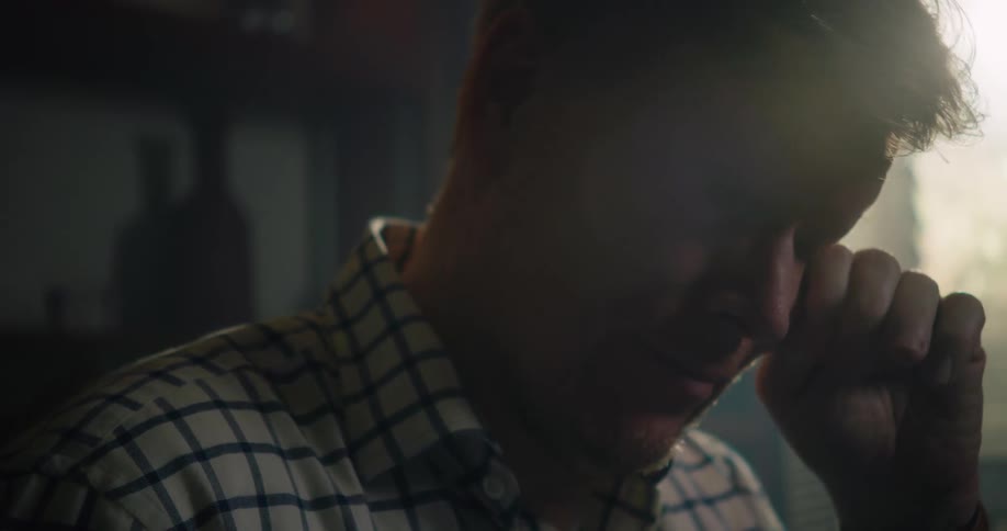 A man takes off his glasses and rubs his eyes with his hand and puts them back on his face