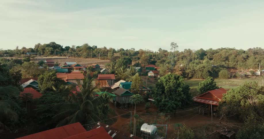 Village sits in area bordering jungle under a cloudy sky