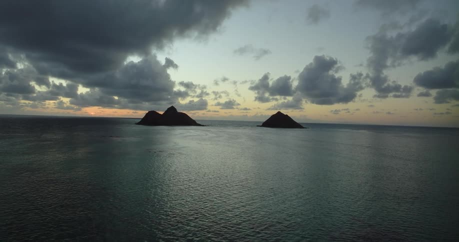 An aerial view of an island in the ocean as the sun sets