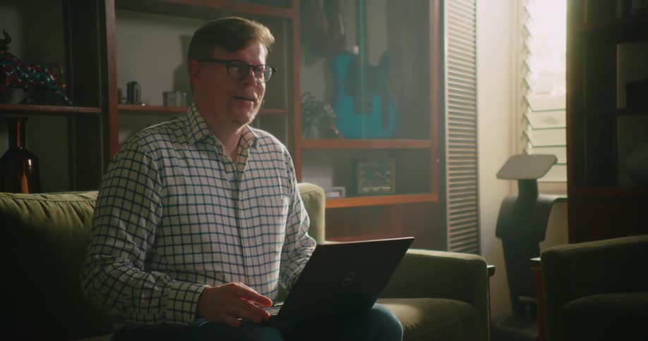 A man looks upset and sighs deeply as he types on a laptop