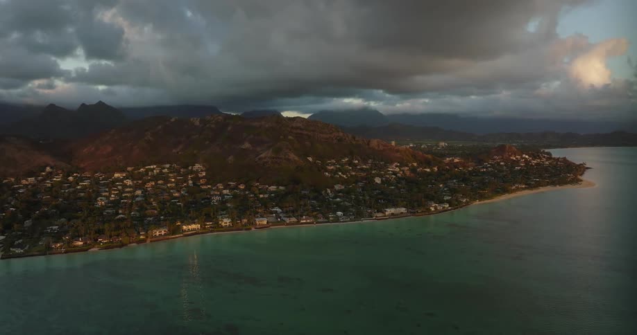Thick clouds loom over a city on the coast in the evening