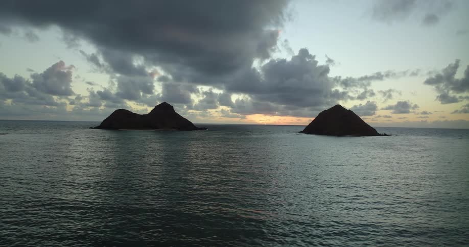 The water ripples and waves as islands of rock formations are in the distance under a cloudy sky
