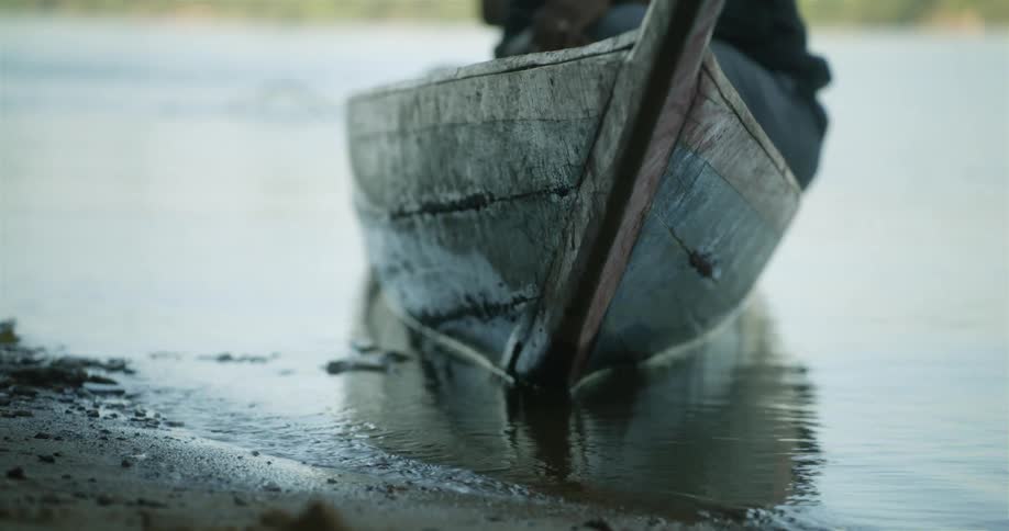 One of the passengers in a small boat floating near the shore gets out