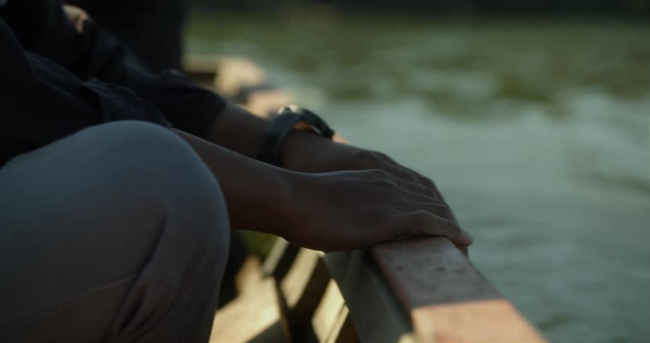 A man holds onto a boat while riding through a lake