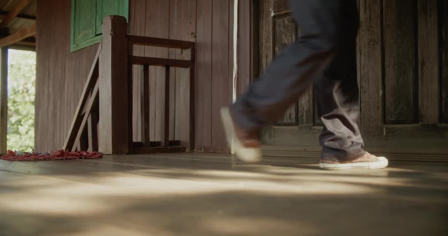 A man walks up the steps to a log cabin