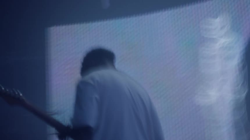 Bright colors and projected media play behind guitarist during performance