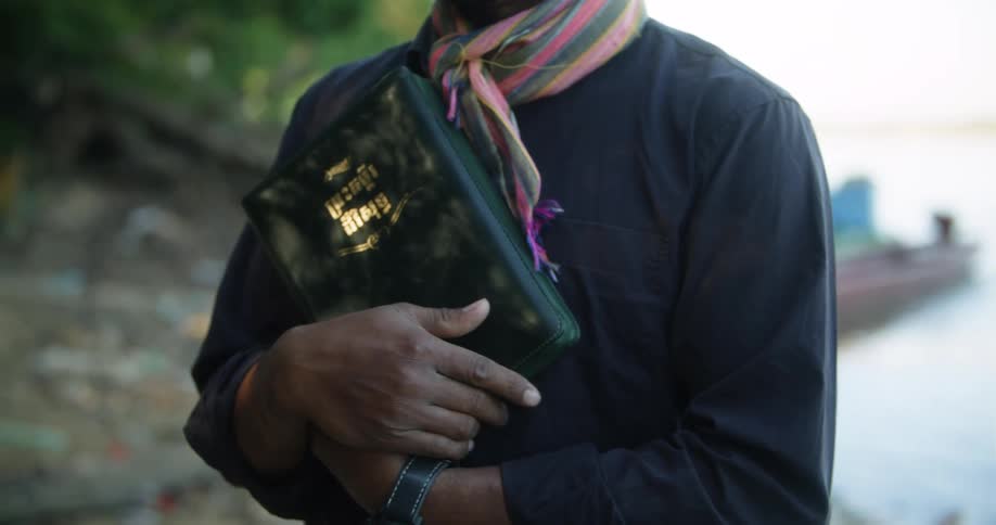 A man hands another man a bible and pats him on the back