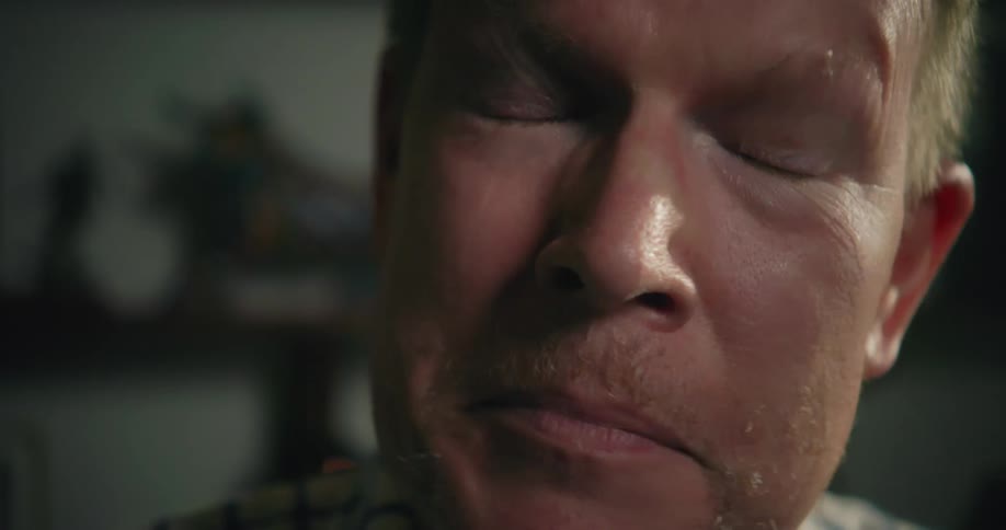 A man takes off his glasses and rubs his eyes with his hand