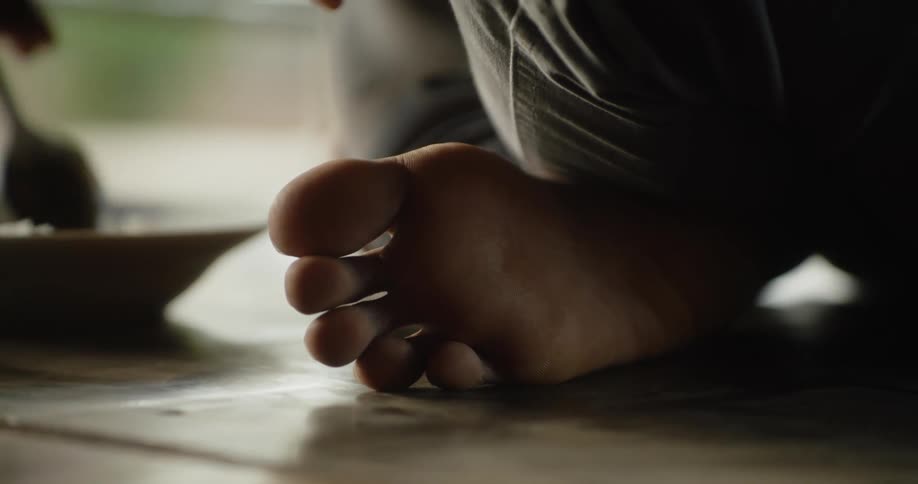 A person sits on the floor and eats out of a bowl
