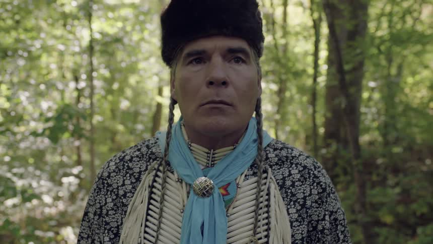 A man wearing a fur cap and walking through the woods