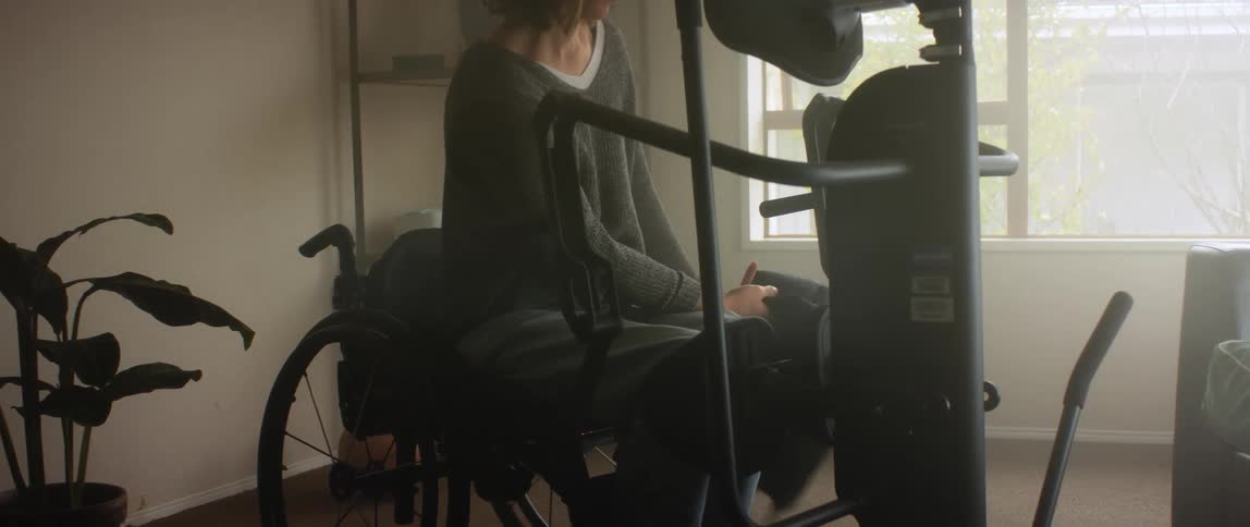 A woman attaches a harness getting up from her wheelchair
