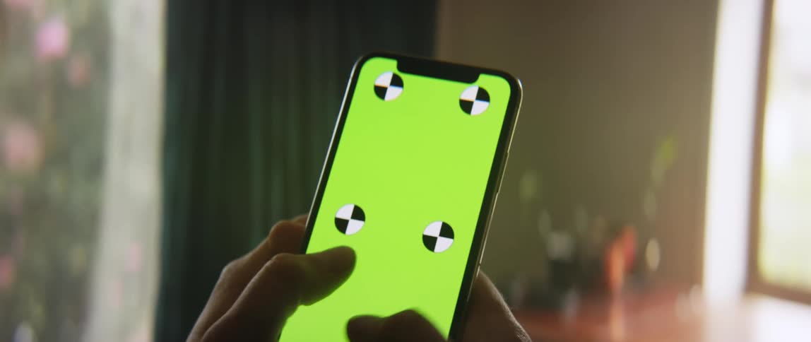 Someone is holding a cell phone with both hands and moving their thumbs across a green screen