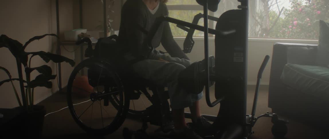 A handicapped woman sits on an exercise bike and gets herself into position before pulling on a lever