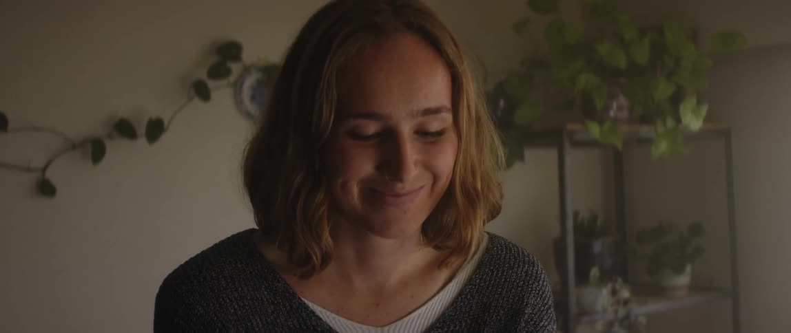 A woman at home smiles as she looks down