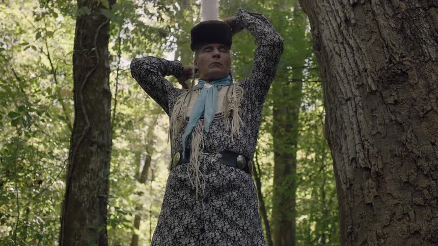 Tribal man placing a piece of headgear on his head in the forest