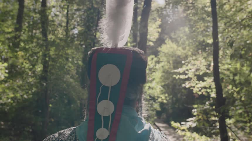 A black and white feather sticks out of a man's headpiece