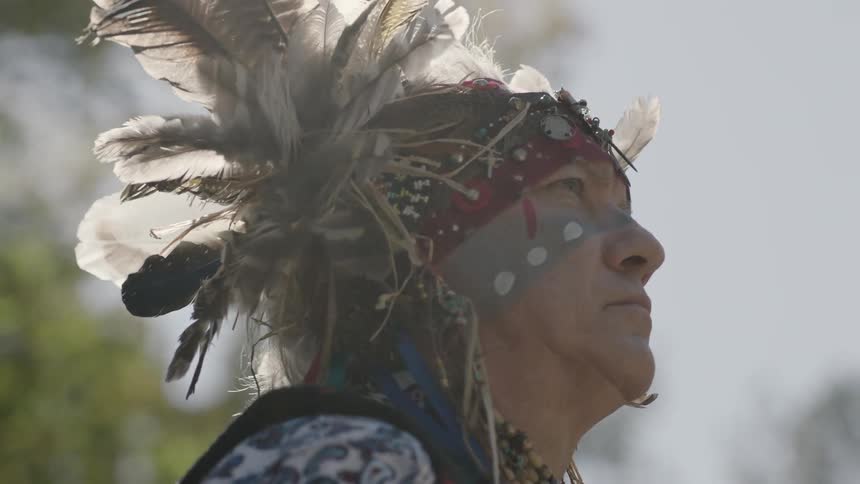 A man with a tribal headdress is standing outside
