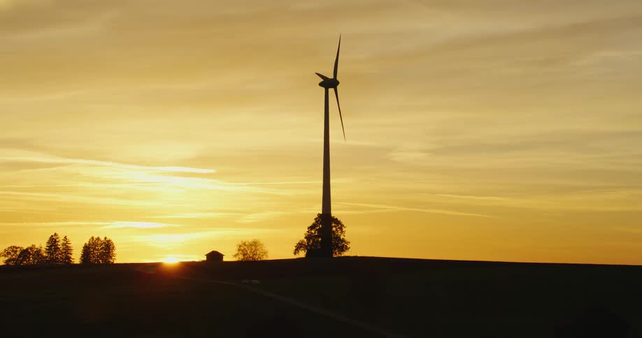 A rotating wind turbine at sunset