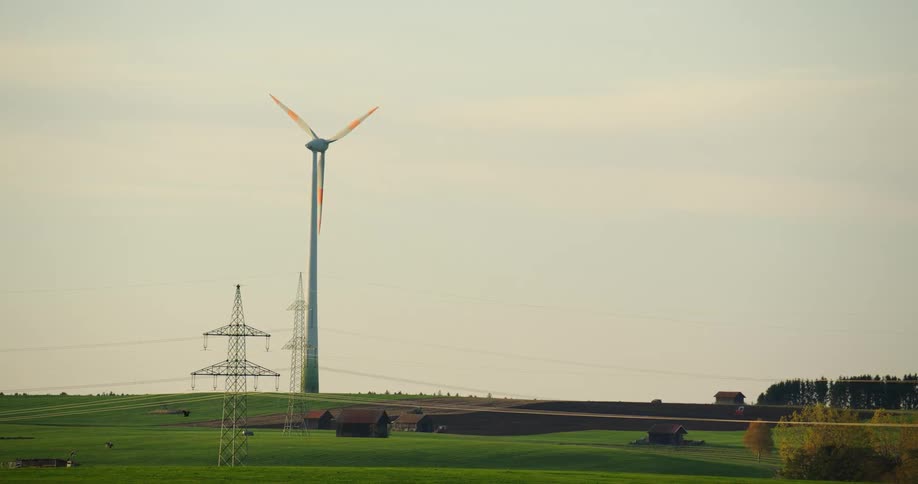 A wind turbine and an electrical tower in a field in a rural area