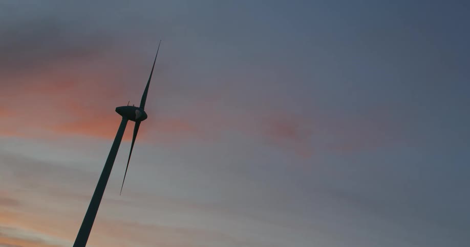 A wind turbine sits near a barn on a farm