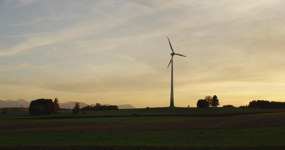 A wind turbine slowly spins in a field