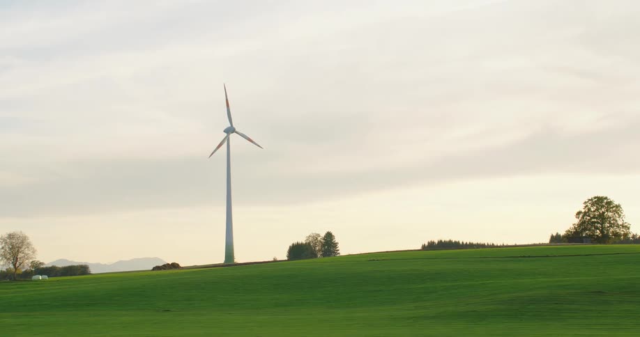 A single wind turbine spins slowly in a field
