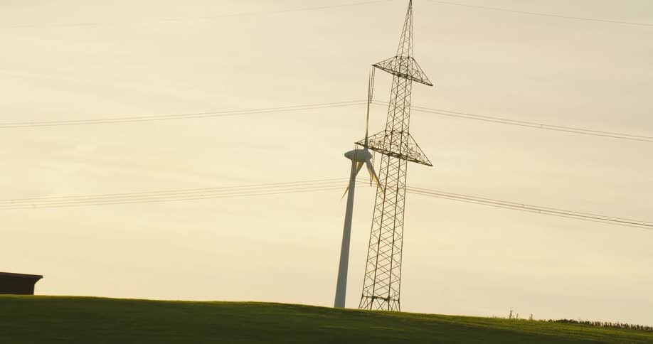 A wind turbine and an electrical tower in a field