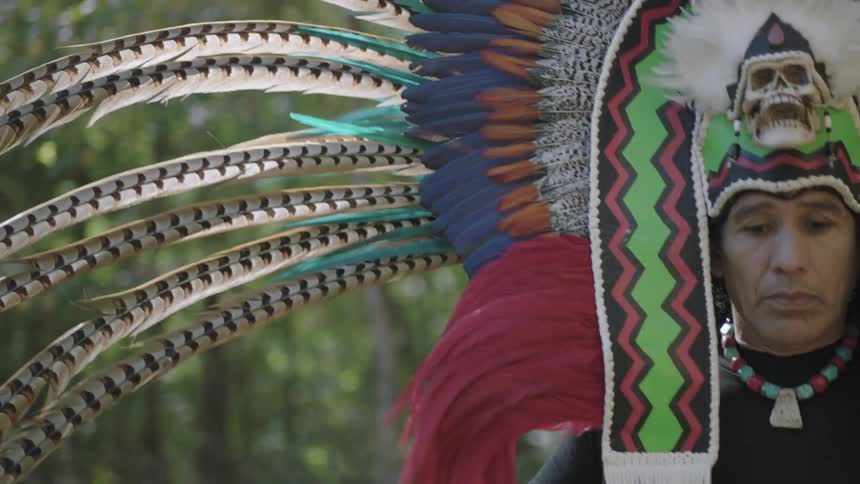 Man dances wearing an elaborate headpiece with moving skeleton