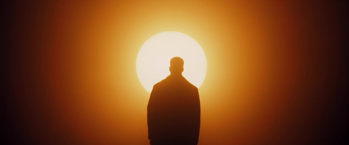 Sun rises above mans silhouette as he walks toward it
