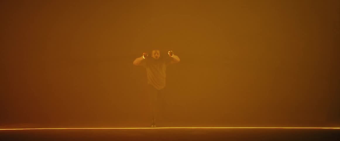 A man dances on stage under bright lights