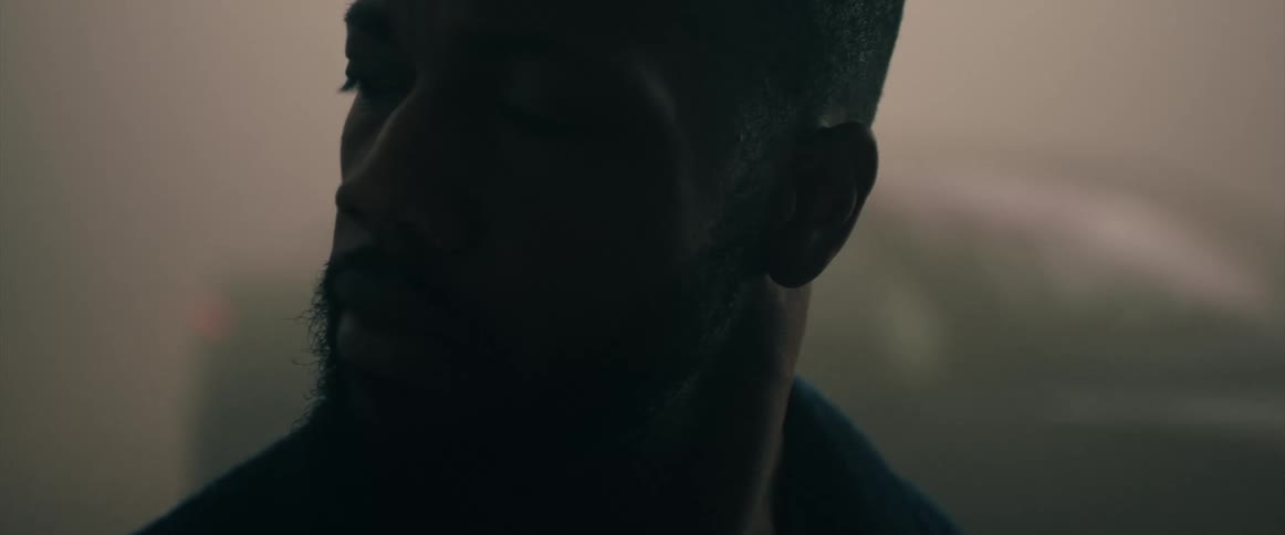 Man with beard and earrings looks over his shoulder