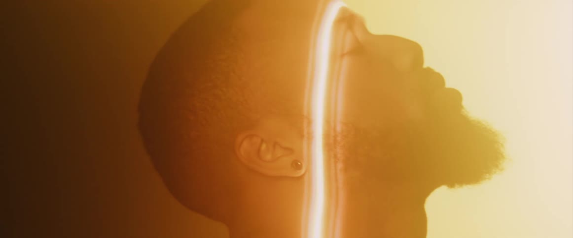 Footage of a man moving his head through a bright beam of light