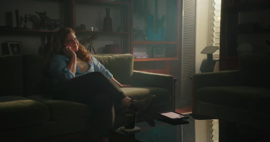 A woman laughs while talking on the phone on her couch